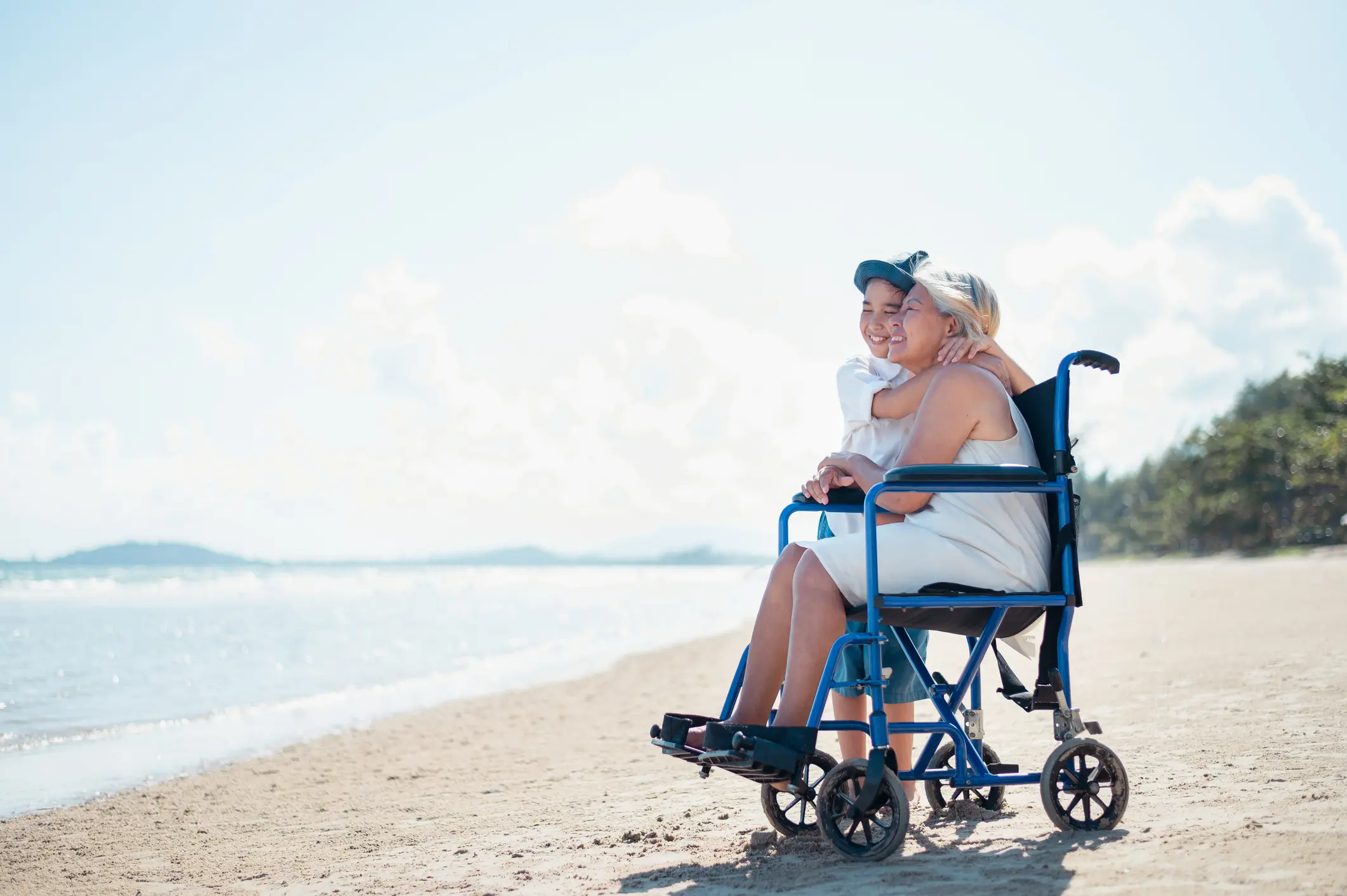 Grandchildren sit with the neighborhood on a wheelchair relaxing on the beach. Grandchildren sit with the neighborhood on a wheelchair relaxing on the beach.