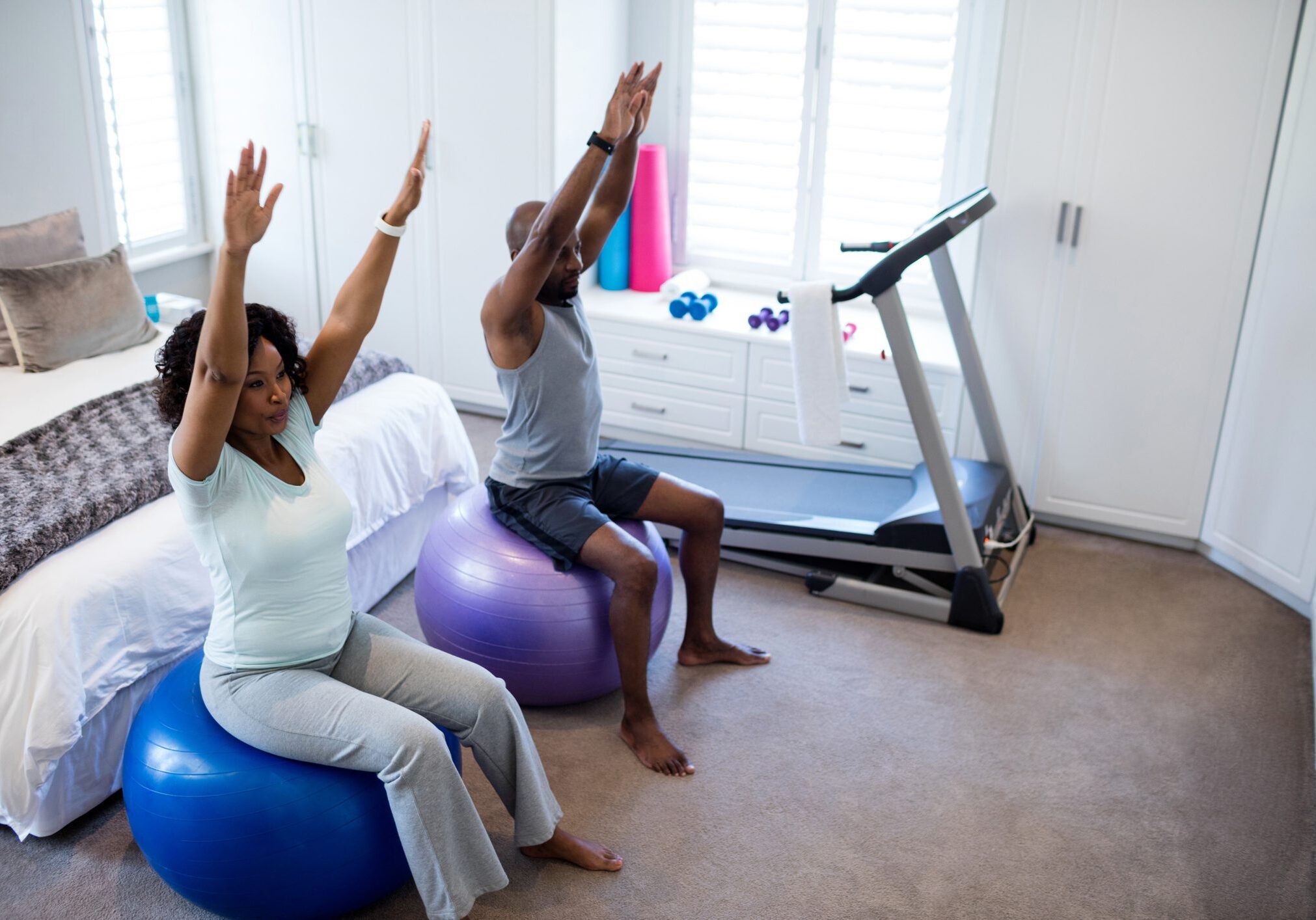 Couple exercising on fitness ball in bedroom Couple exercising on fitness ball in bedroom at home